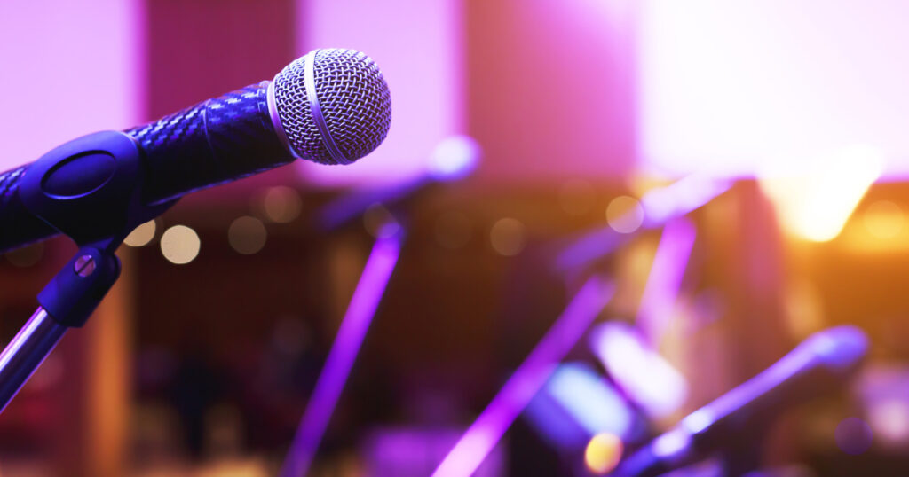 Close up of microphone on stage lighting at concert hall or conference room. copy space banner. soft focus.